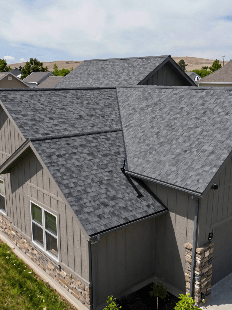 Wide angle shot of a suburban home in Colorado with a newly installed charcoal grey shingle roof, lush green lawn, bright daylight, North American / US.