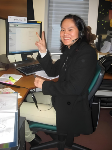 a woman sitting at a desk with a computer and a laptop