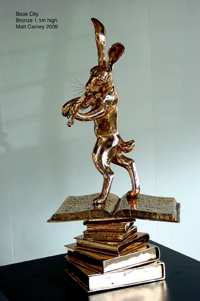a bronze statue of a rabbit on a stack of books playing the violin