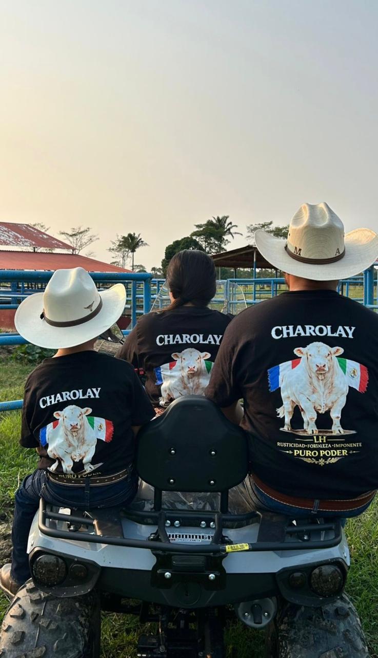 Family wearing Charolay cattle shirts and cowboy hats sitting on an ATV at a ranch.