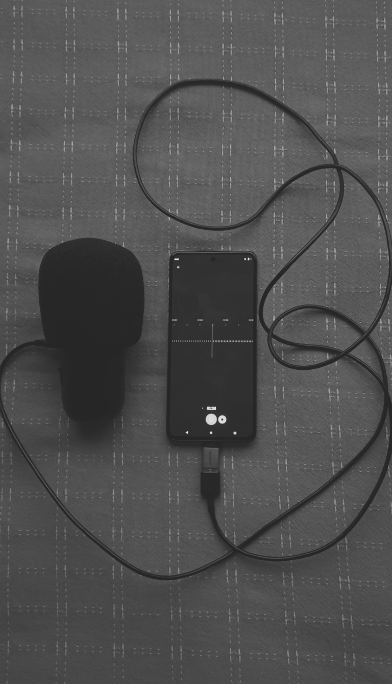 Micrófono oscuro conectado a un celular grabando un audio