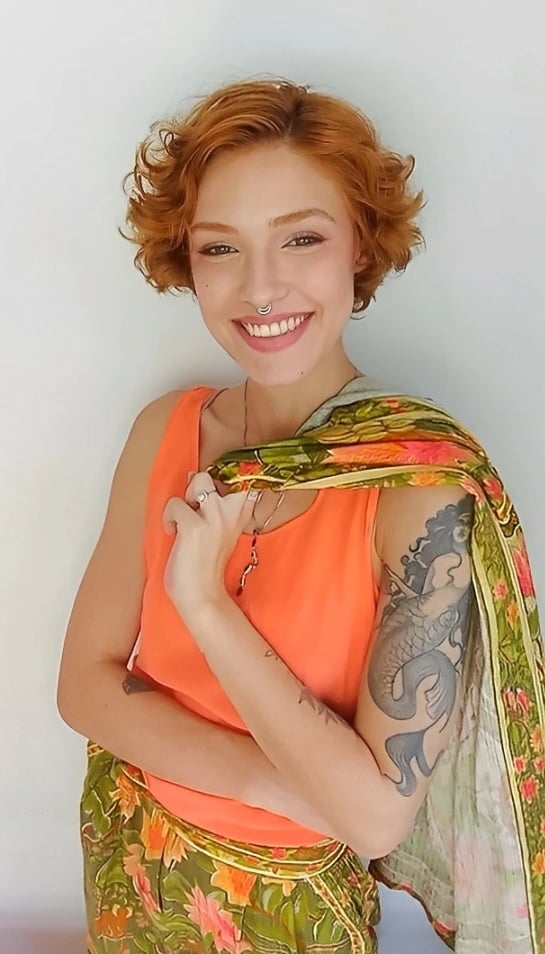 Sabrina Tibursky sorrindo carregando em uma mão um casaco sobre os ombros