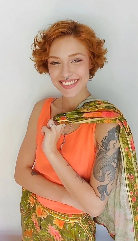 Sabrina Tibursky sorrindo carregando em uma mão um casaco sobre os ombros