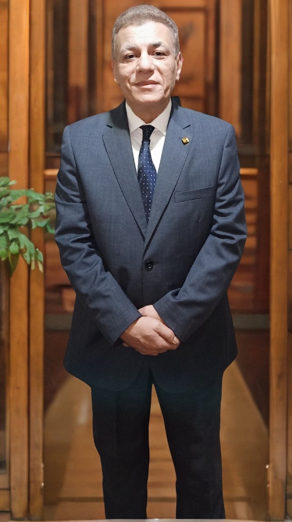 Major General Ayman Syedelahl stands wearing an elegant grey suit, with luxurious office decor