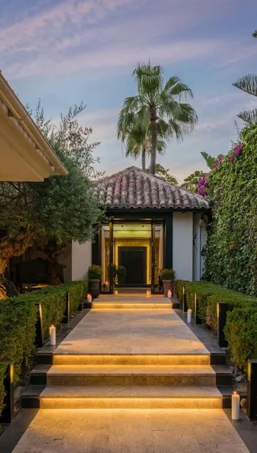 Illuminated entrance pathway framed by lush greenery and palm trees at Villa El Olivo, Marbella