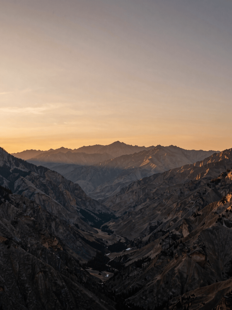 A wide-angle sunrise shot over a North American mountain valley, with the peaks glowing in a muted bronze light. The composition is balanced and simple, showcasing the vast beauty of nature in a professional photography style.