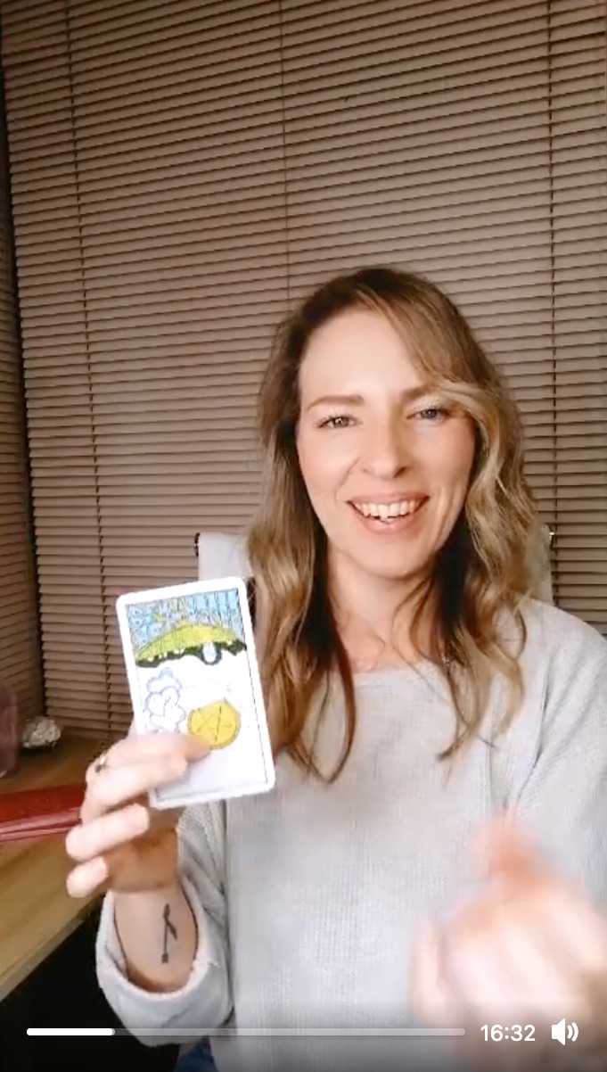 Natalie holding the Ace of Pentacles reversed during a live tarot reading.