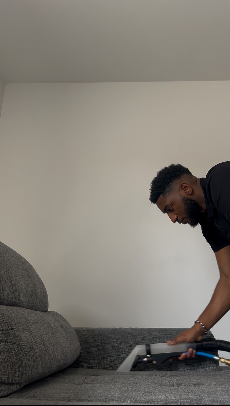 a man is cleaning a couch with a vacuum