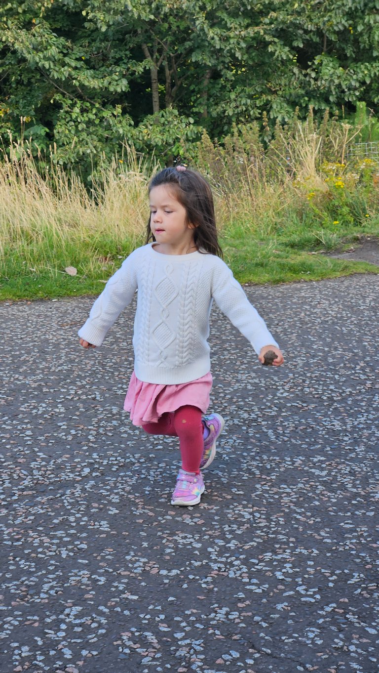 Girl running in Scotland in layered capsule wardrobe during a family trip to Europe