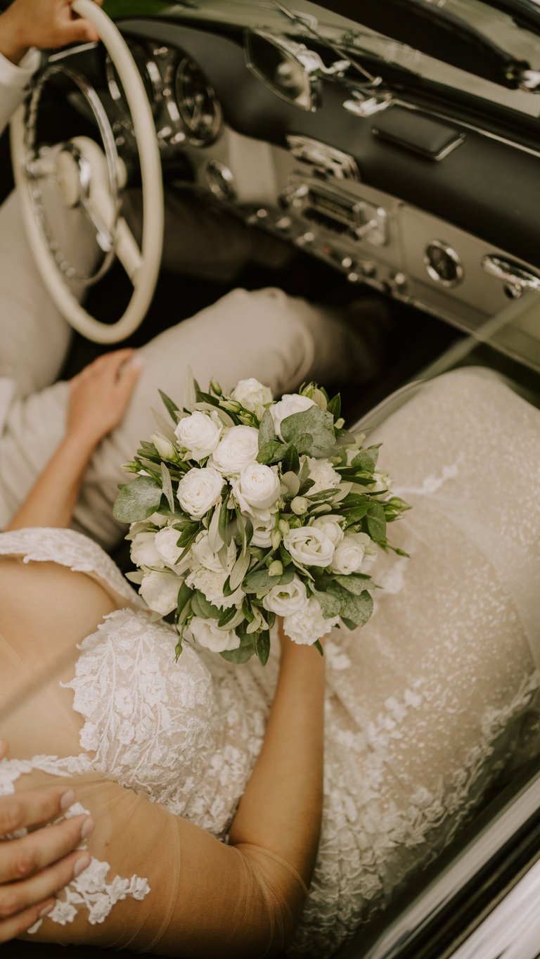 Emotionale Hochzeitsfotografie in Rheine: Die Braut im Oldtimer mit Strauß