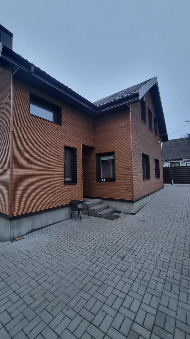 Namo fasadas renovuotas padengiant jį horizantaliomis medinėmis lentelėmis.