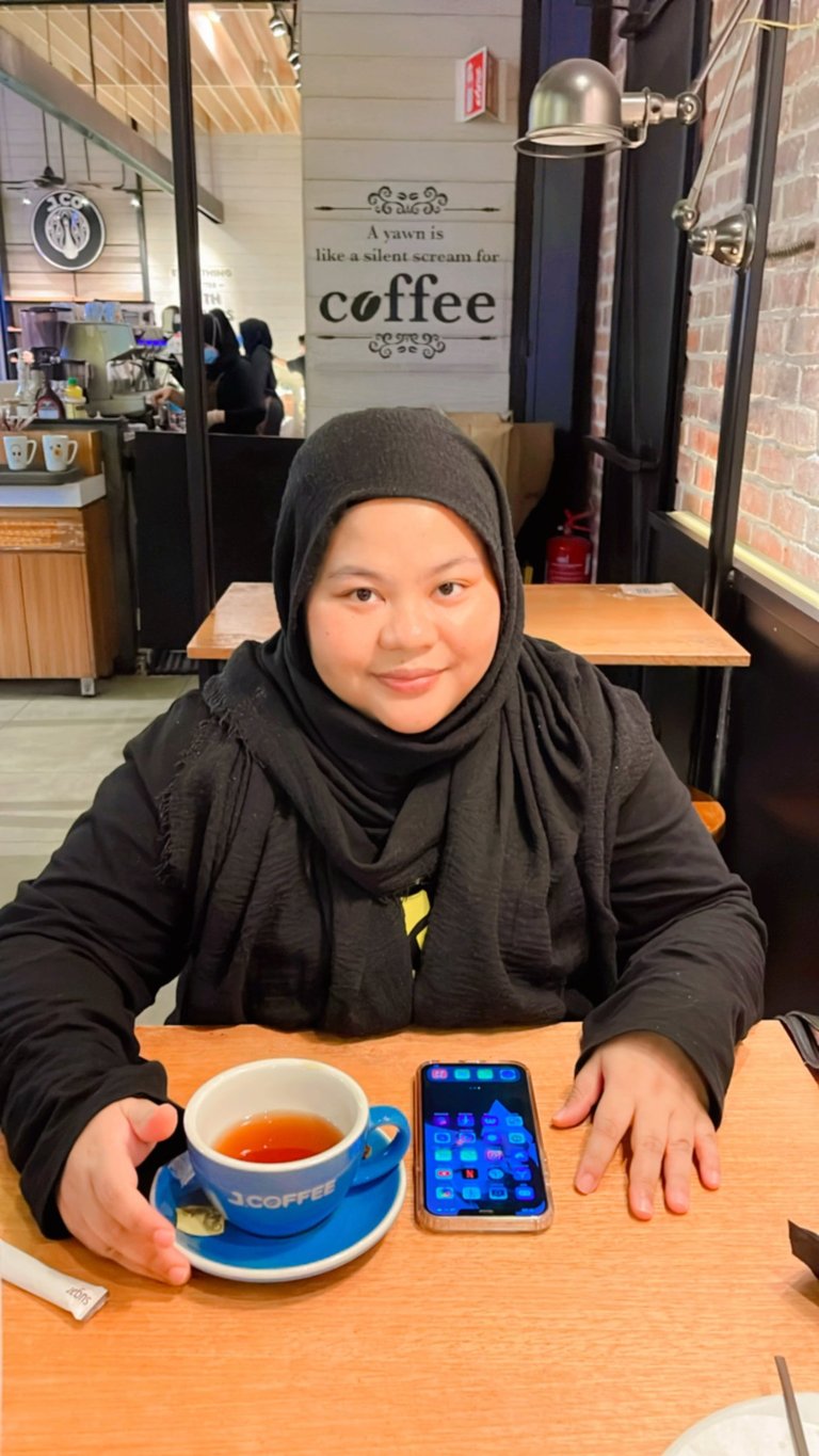 Female in black shirt and hijab in a cafe