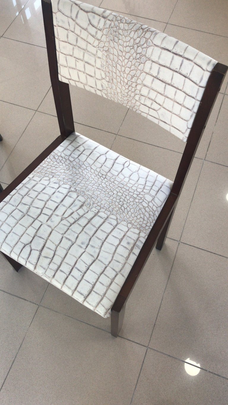 Silla antigua tapizada con terciopelo imitación piel de serpiente integrándola en espacio moderno. 