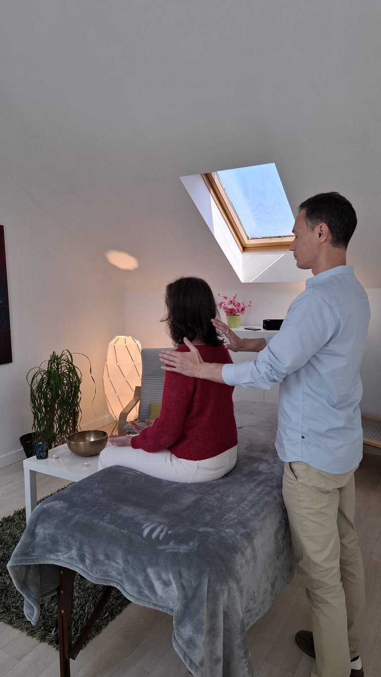Femme assise recevant un soin énergétique dans un cabinet chalereux.