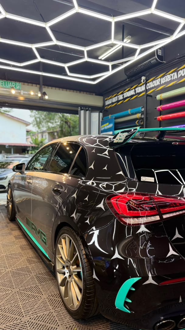 Mercedes AMG hatchback with white geometric decal wrap and teal accents