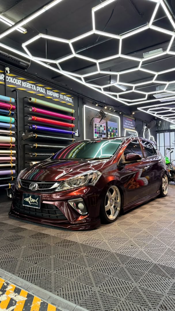 Perodua Myvi wrapped in gloss maroon vinyl with gold rims