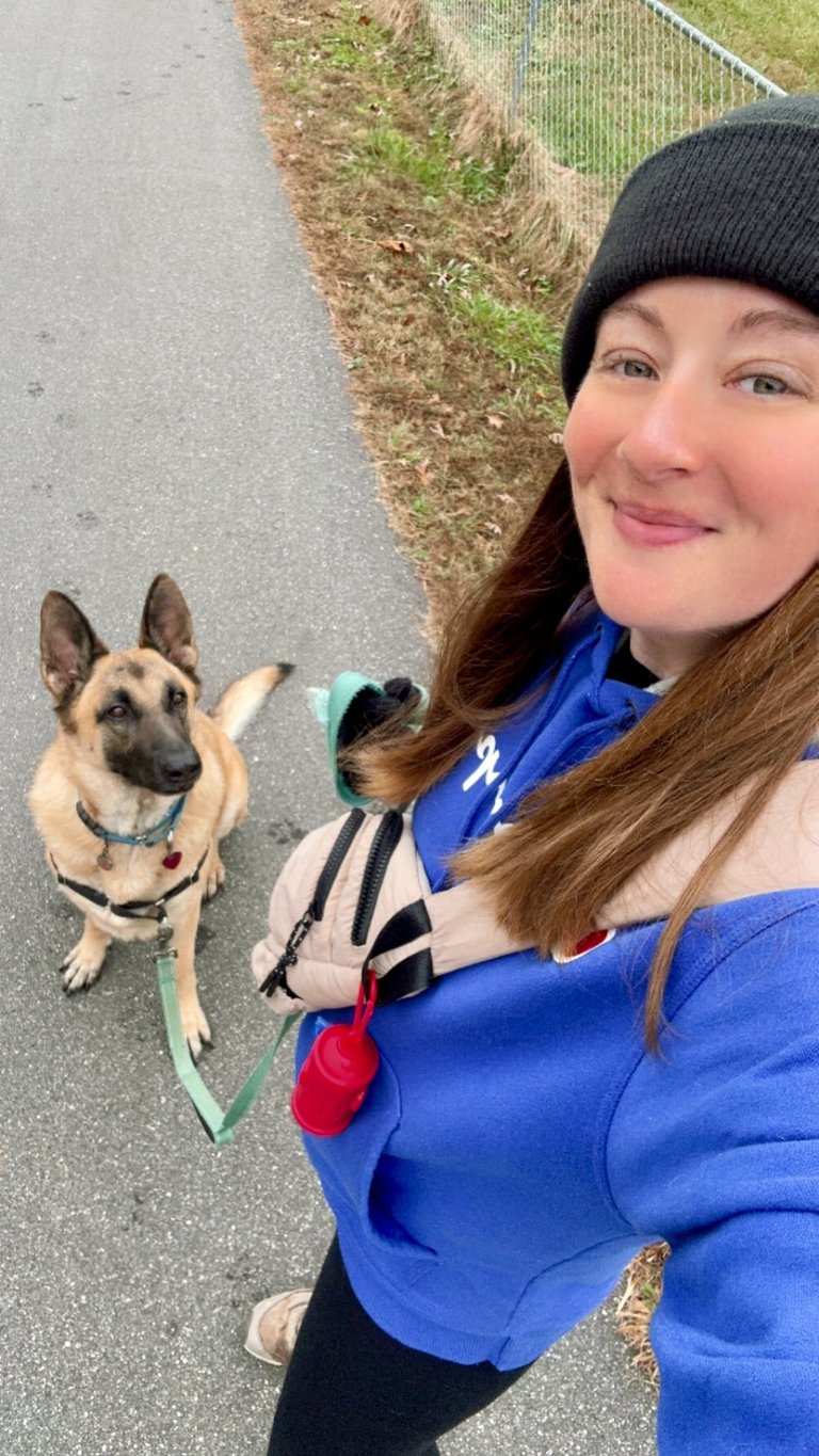 a woman in a blue jacket and hat with a dog on a leash