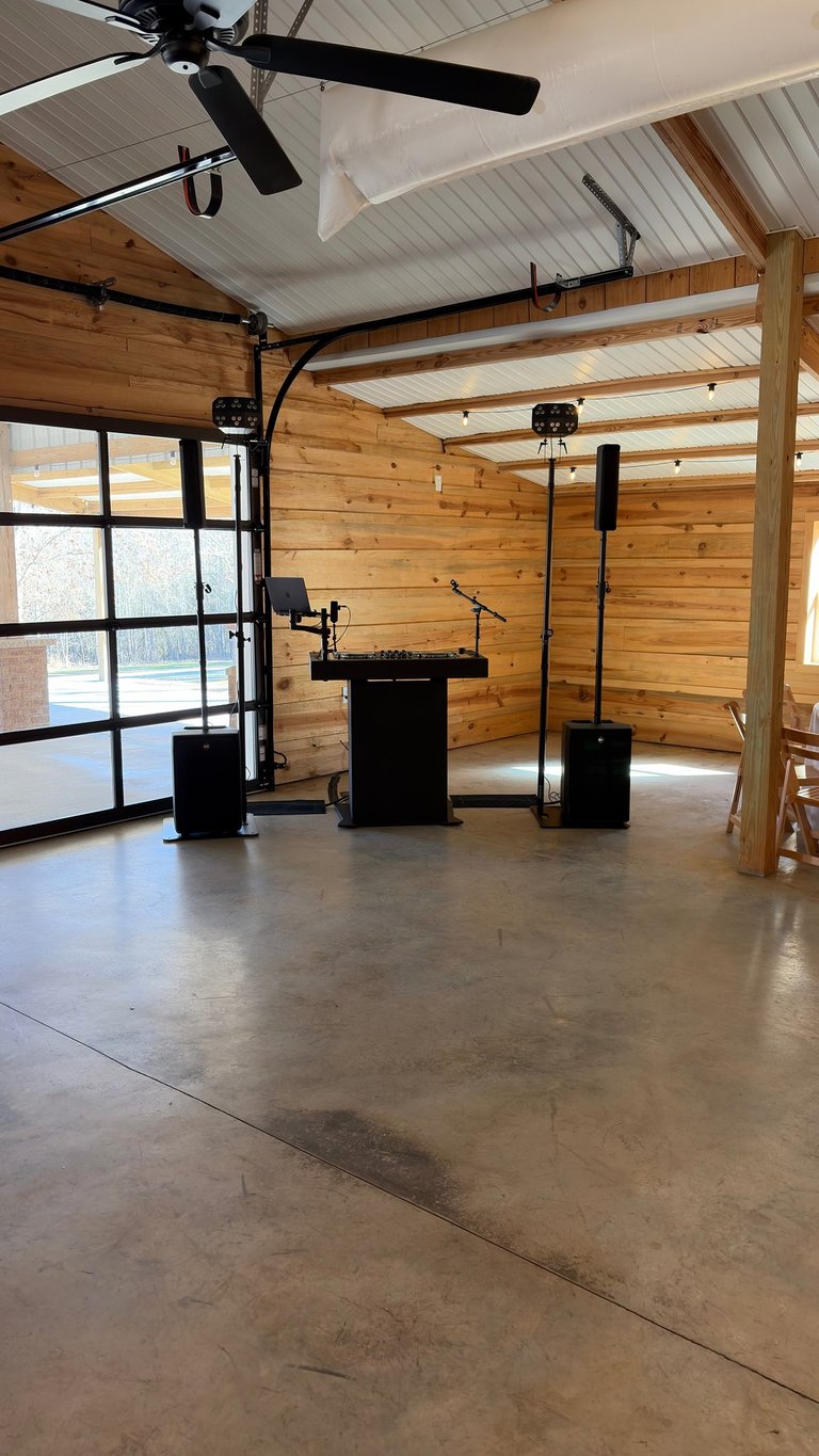 Professional DJ setup with a black booth, speakers, and blue party lights in a rustic wooden venue.