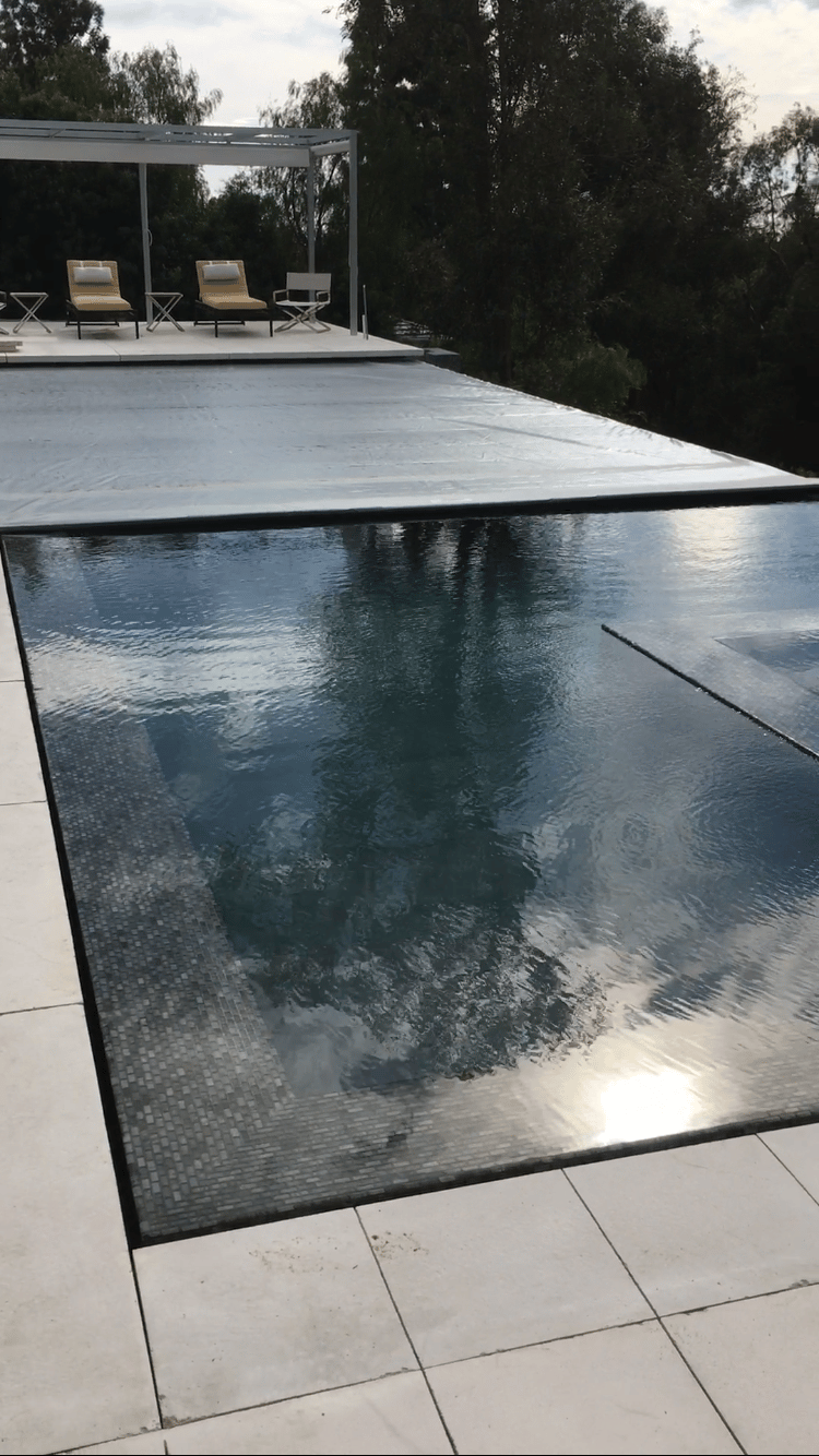 a perimeter flow pool with an automatic pool cover and a sky view 