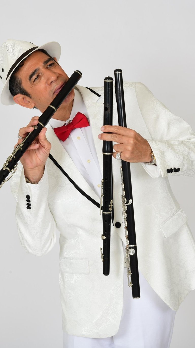 Maestro Bobby Ramirez in white suit playing flute