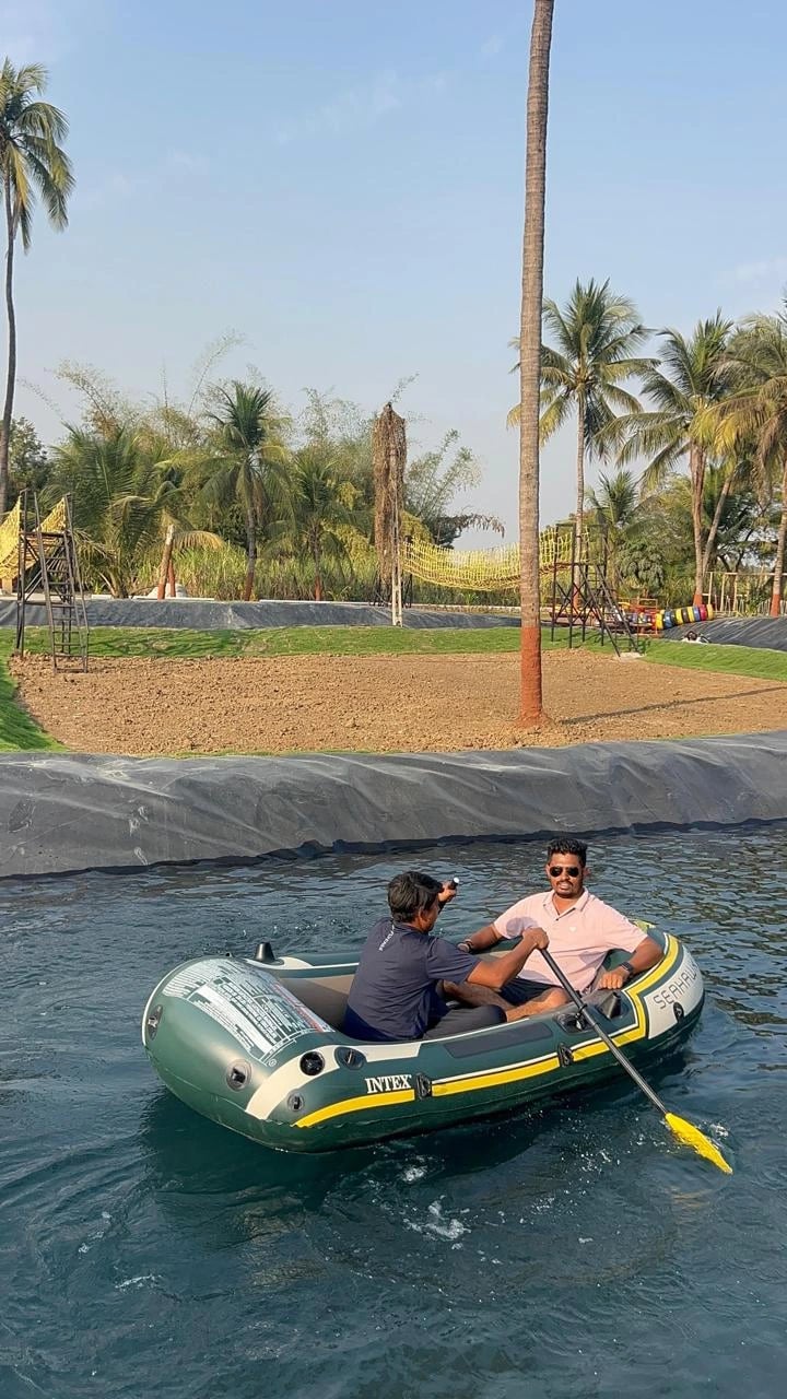 One-day picnic near Surat: Two people enjoying a relaxing boat ride on calm water, surrounded by palm trees