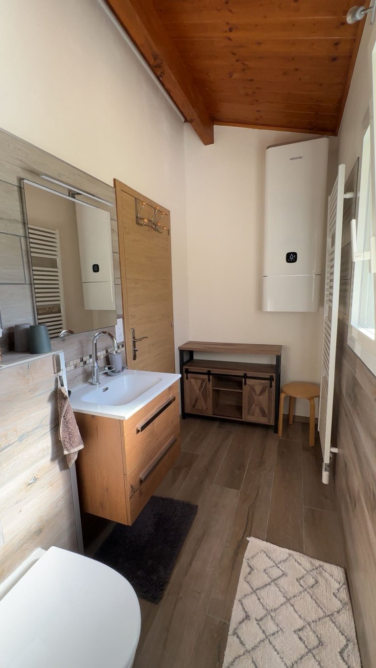 Salle de bains avec grand chauffe-eau et sèche-serviettes fonctionnel.
