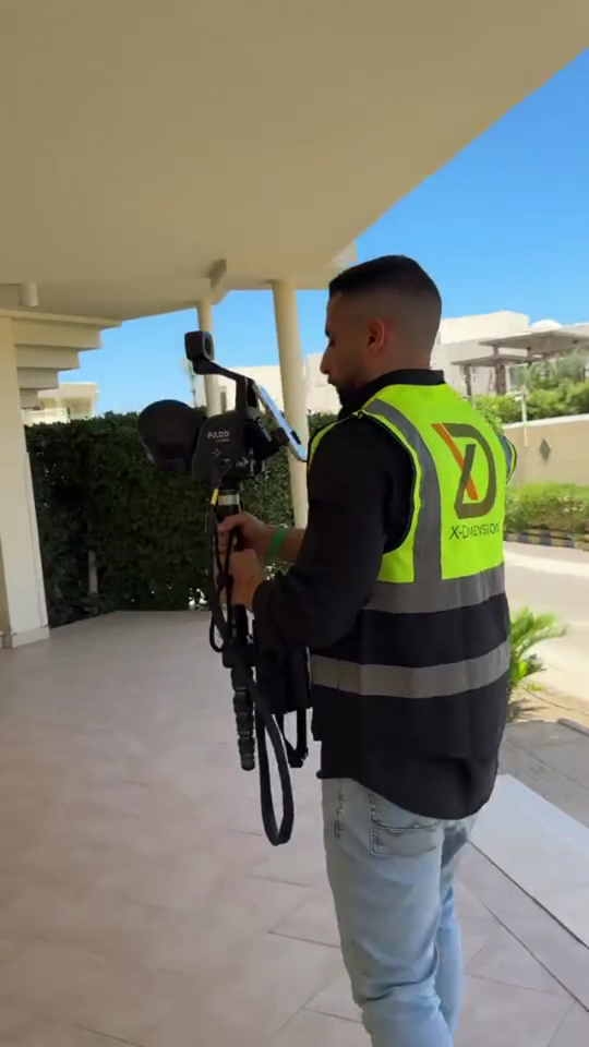 Engineer in a high-visibility safety vest operates a FARO 3D laser scanner on a tripod for hotel.