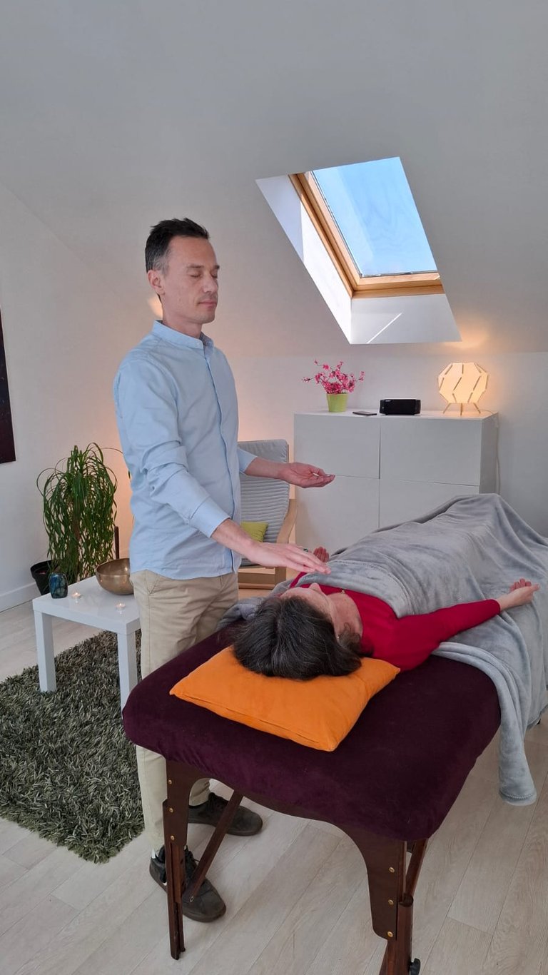 Énergéticien faisant un soin énergétique à une femme allongée sur une table de massage.