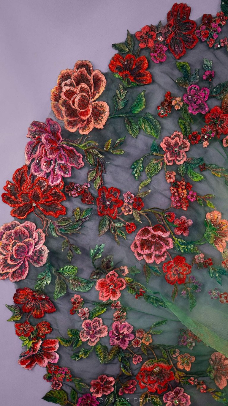 Close up of lace embordered roses painted in vibrant reds and pinks around green leaves