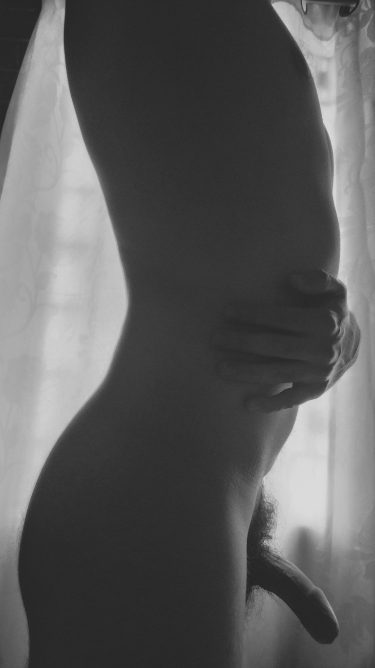 Silueta masculina desnuda y luz: Fotografía artística en blanco y negro de cuerpo y mano.