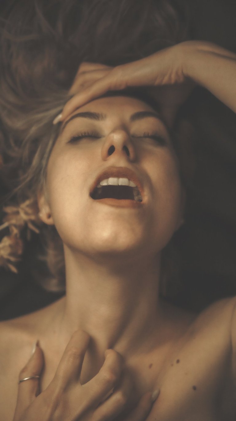 a woman with her eyes closed and mouth open, she holds her hair