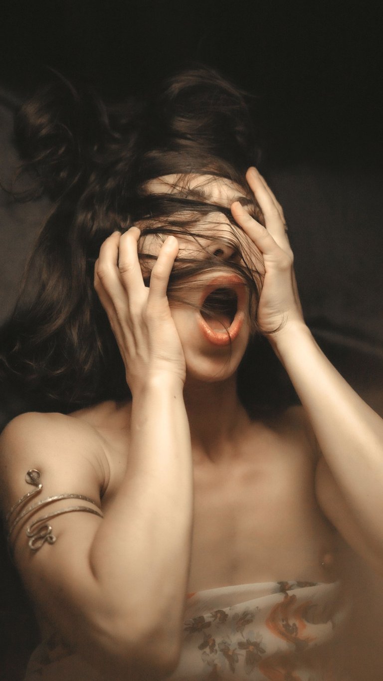 a portrait of a woman holding her head with her hands, she have a mouth open 