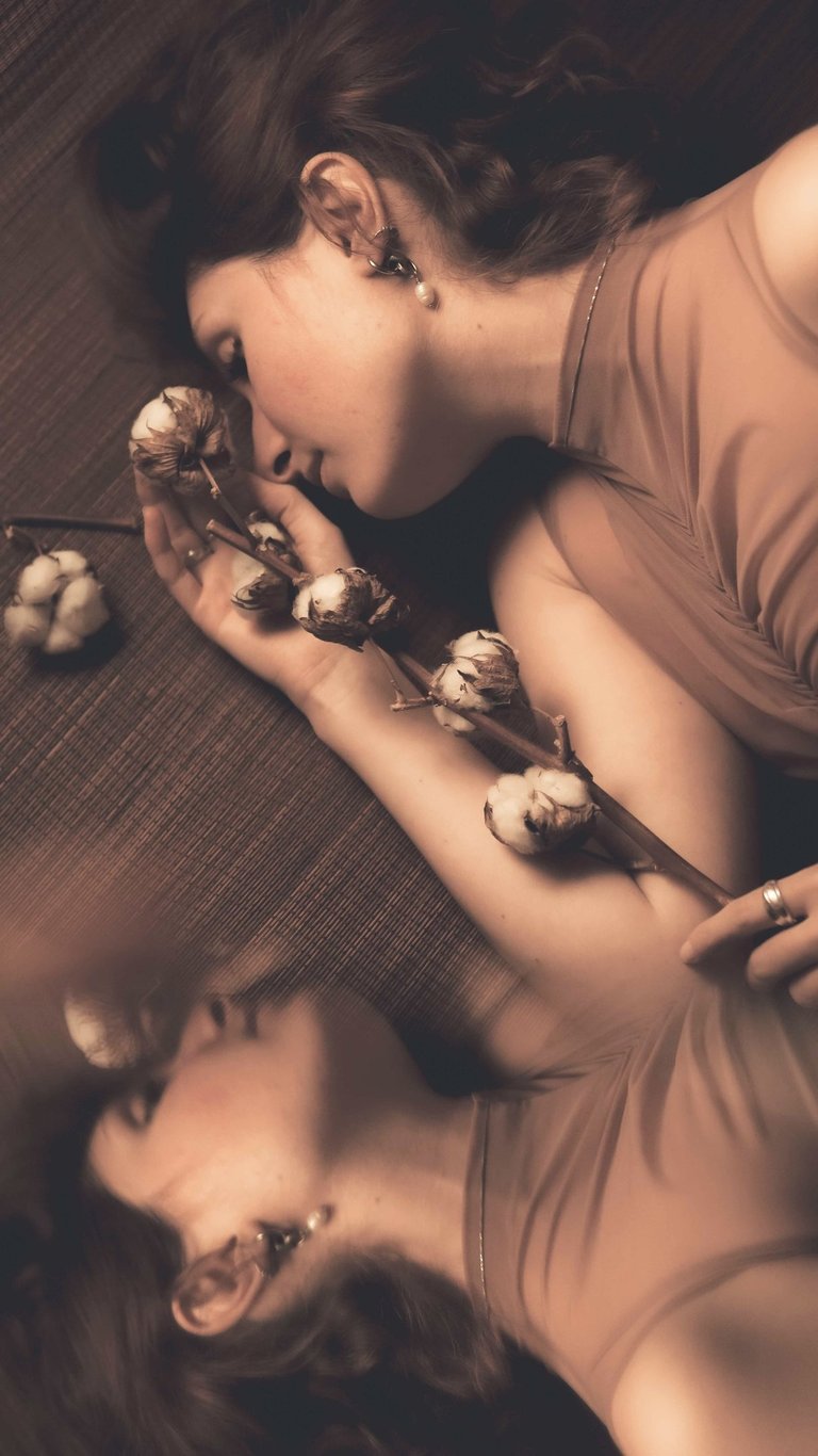 a woman laying on a couch with a flower in her hand and own reflection