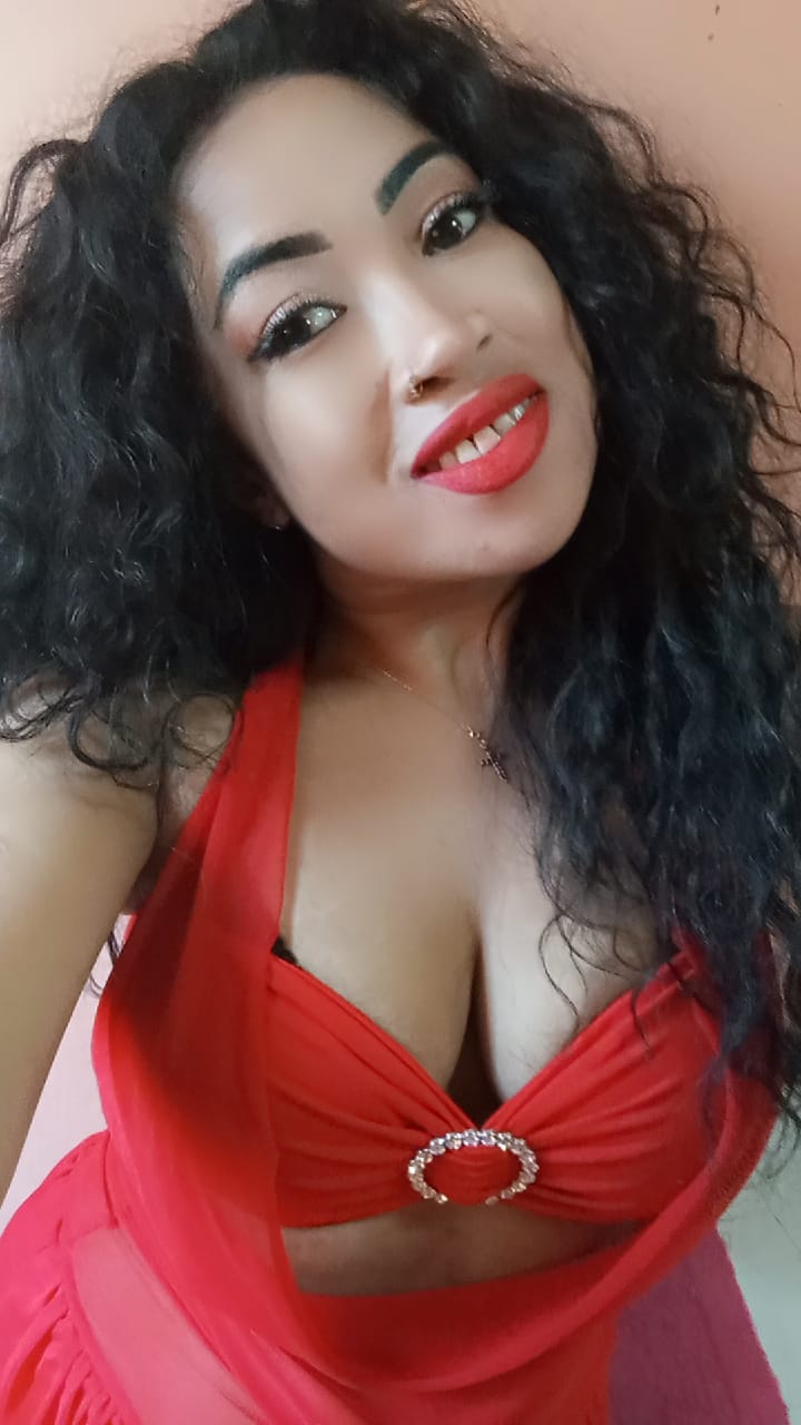 a smiling lady with long black hair wearing a red dress 