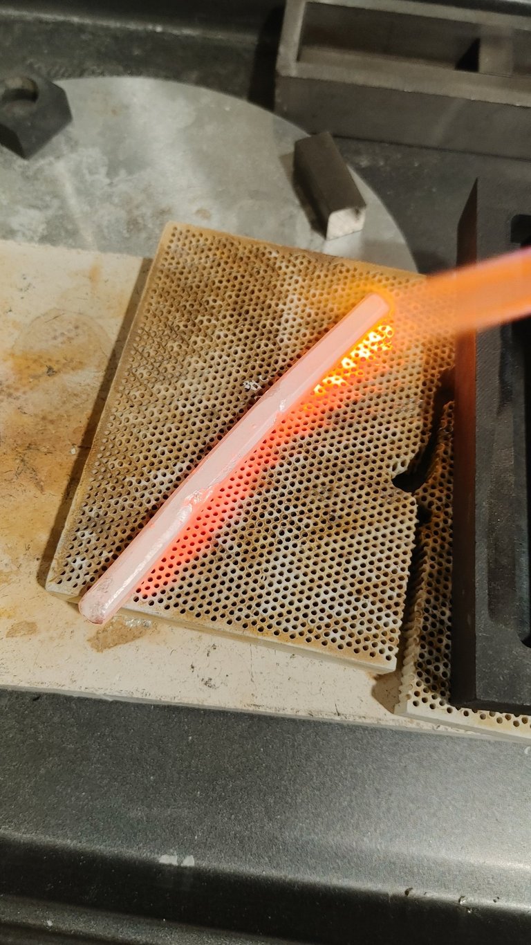 Hot silver piece being quenched in water after heating.