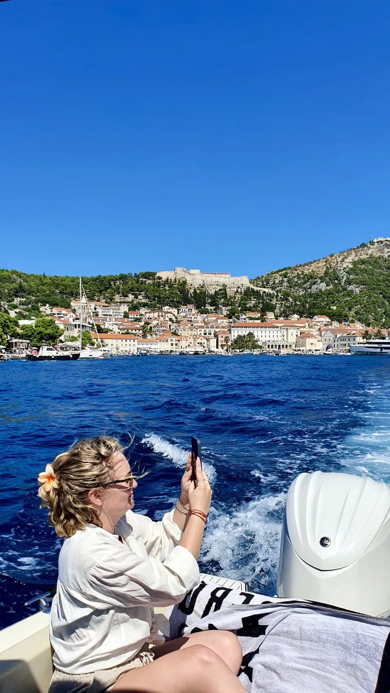 Woman photographing the coastline of Hvar, Croatia and Fortica fortress from a boat on a private tour from Split