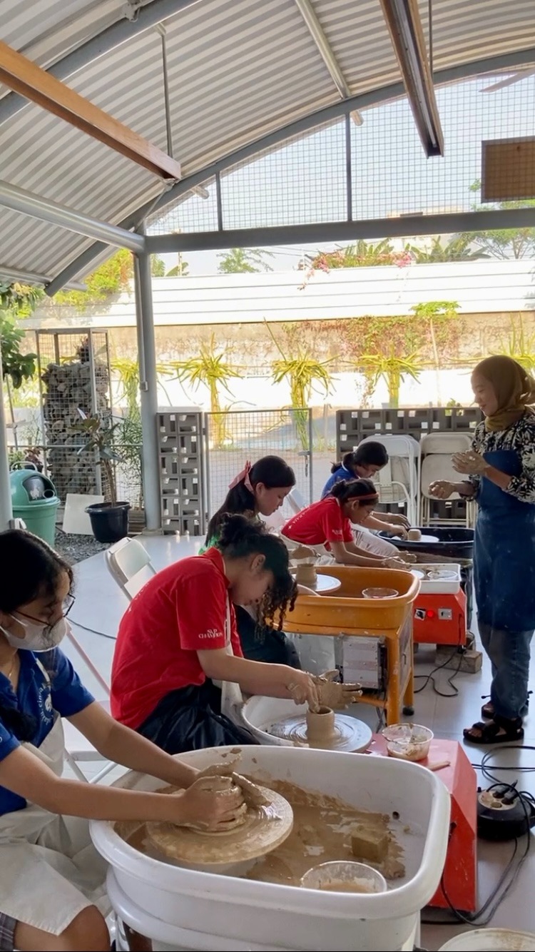 a group of students shaping out clay on pottery wheels