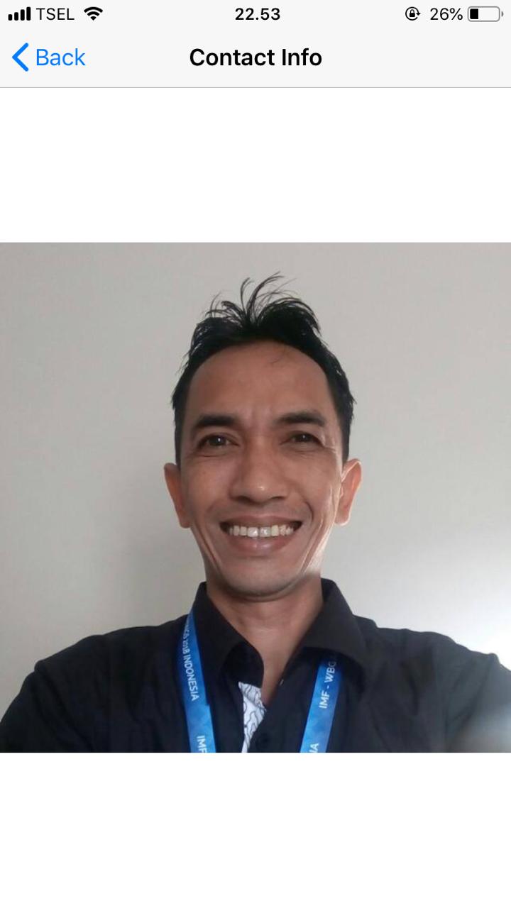 Smiling man in a black button-down shirt with a blue lanyard posing for a professional headshot.