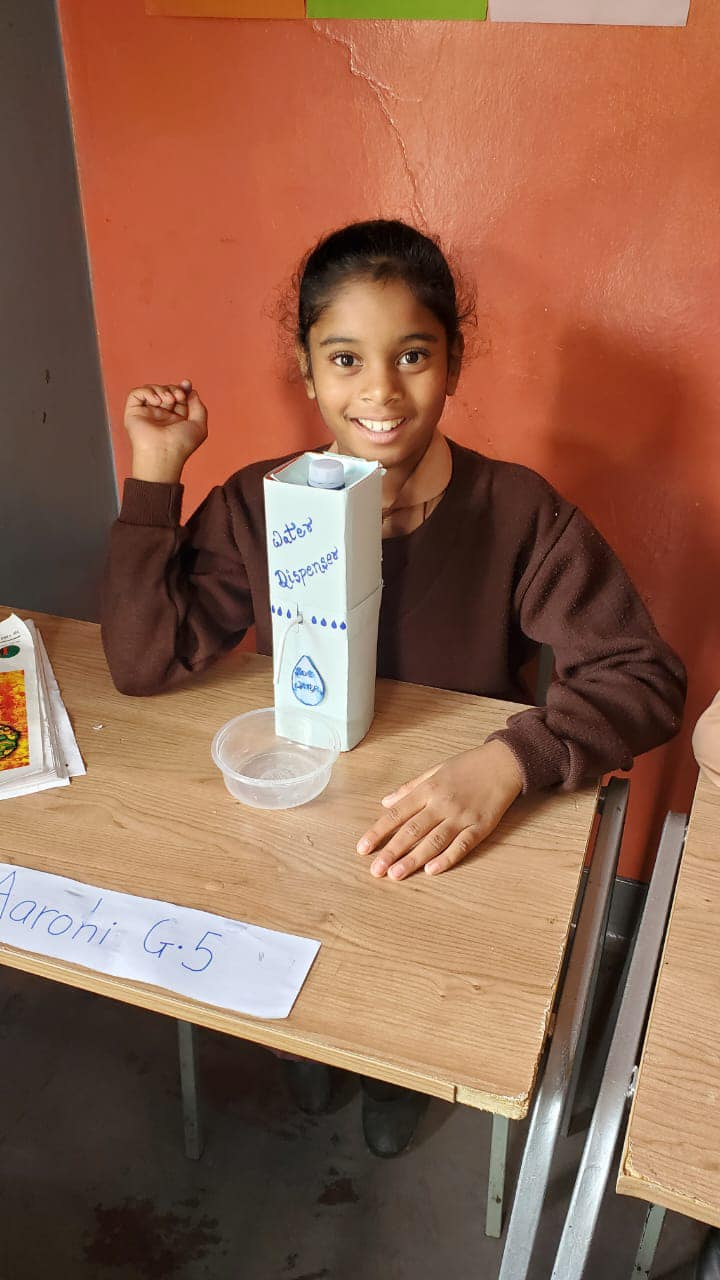 a young girl sitting at a table with a box of milk