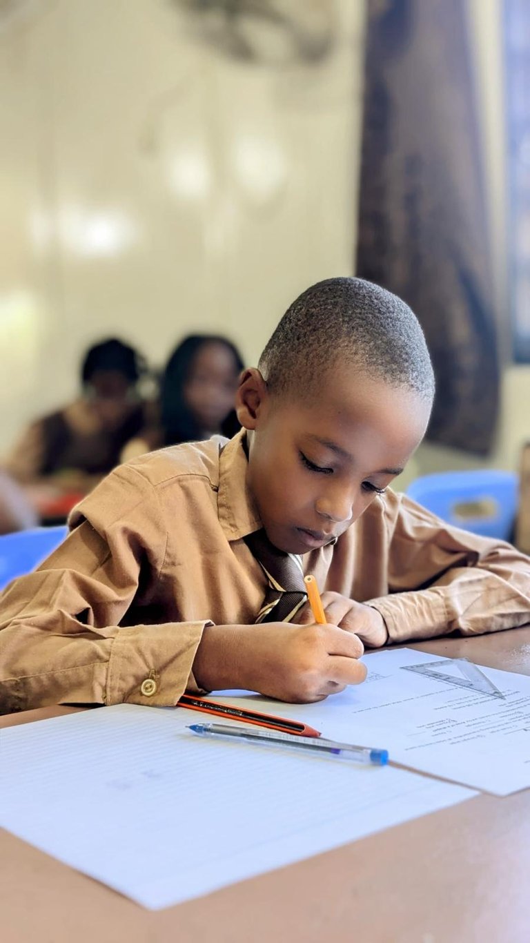 a young boy is sitting at a desk with a pencil and pencil