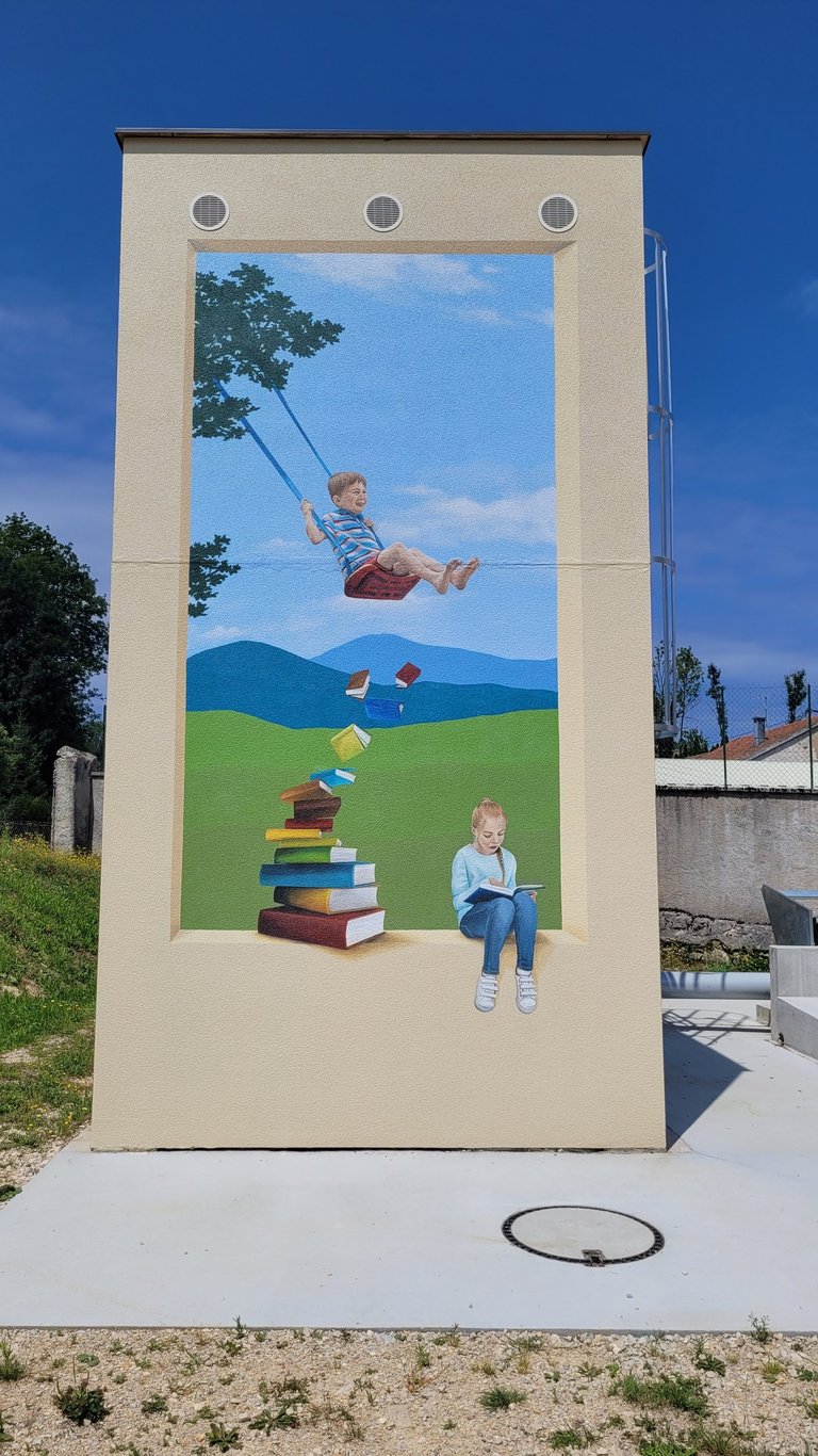 Fresque sur façade. Comme une ouverture dans un mur avec fond paysagé où des enfants jouent.