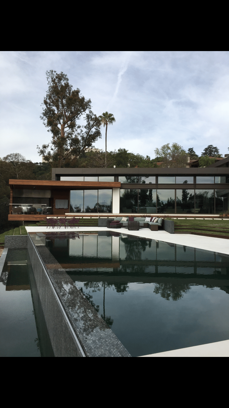 a vanishing edge pool and spa with a view of a large house