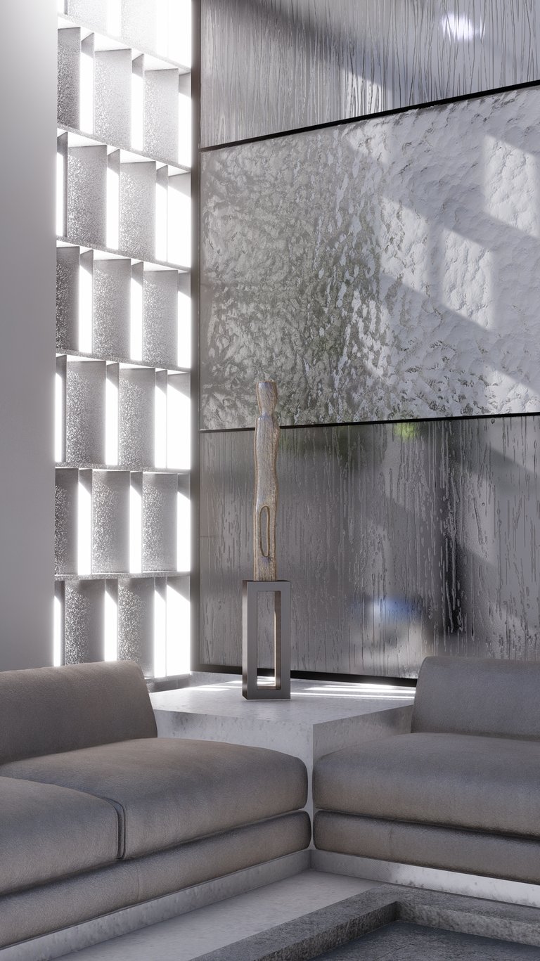 The arrangement of gray sofas and a standing sculpture in front of a modern, textured wall.