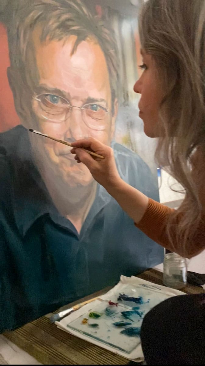 Close up on Stefanie painting on a large oil portrait.