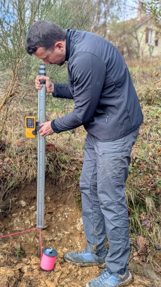 Installateur de fondation sans béton calculant le dénivelé du terrain