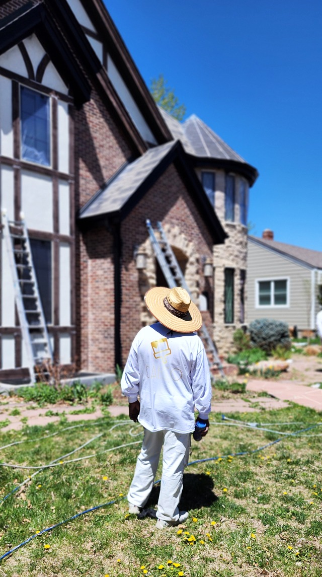 a man in a straw hat painting exterior wearing daeco paintng shirt