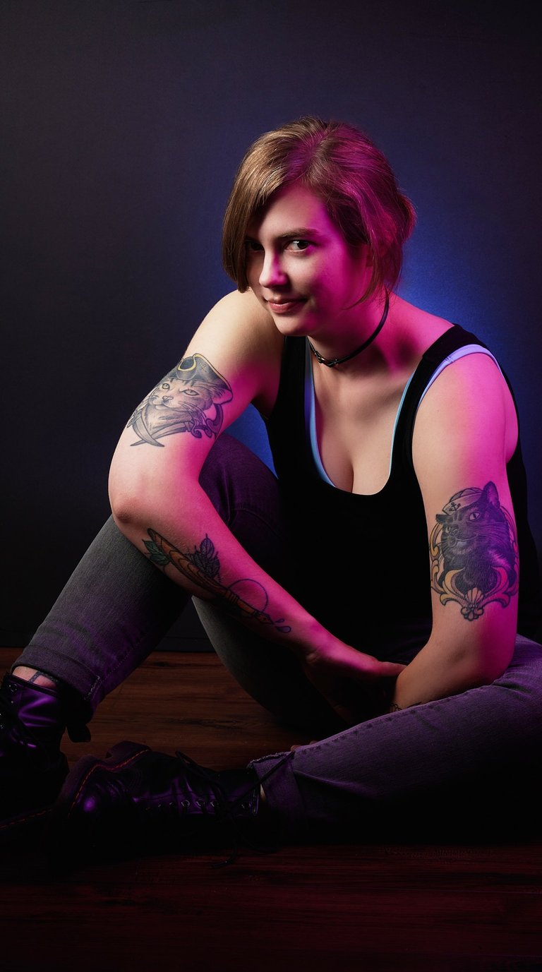 a woman with pirate cat tattoos on her arms in pink color indoor lighting