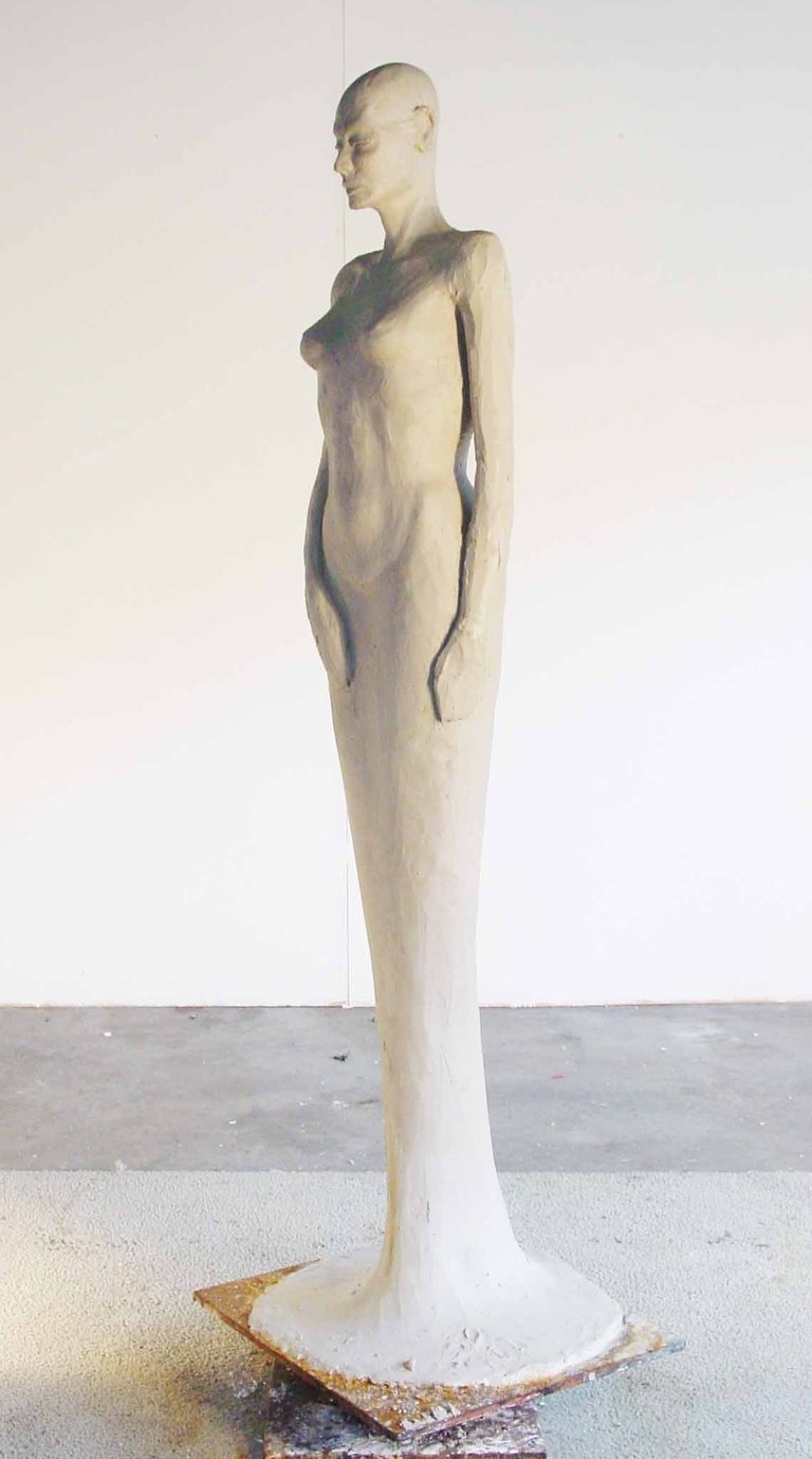 a clay model of a woman standing in a dress