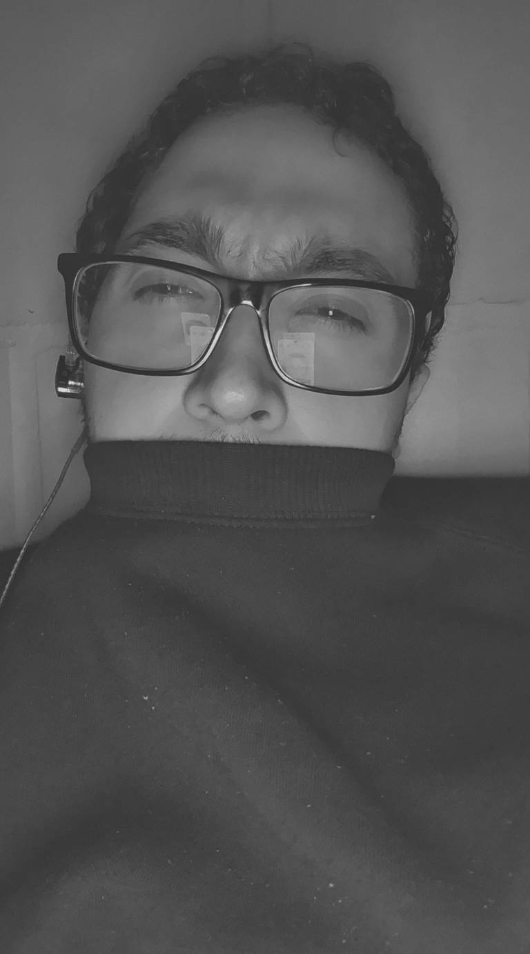 Un primer plano en blanco y negro de un hombre con gafas y jersey de cuello alto.