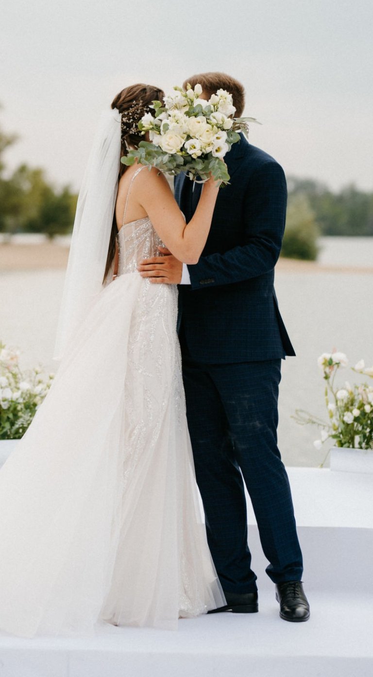 Bride and groom kiss at outdoor ceremony, bouquet raised—filmed by Imack Wedding Films, Glasgow.